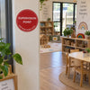 A red circular 'SUPERVISION POINT' sticker on a white pillar in a children's classroom.